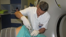 MUDr. Ivo Trtek, lékař odd. radiologie a zobrazovacích metod, při aplikaci ozónu pacientovi ležícímu na pohyblivém stole CT přístroje.